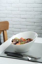 Delicious salad with beef tongue and vegetables served on white wooden table indoors. Space for text