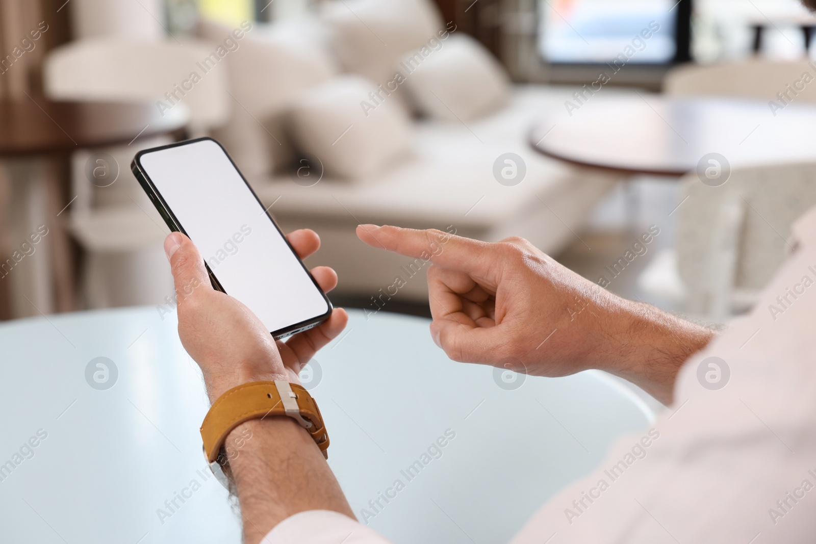 Photo of Man using mobile phone at table indoors, closeup