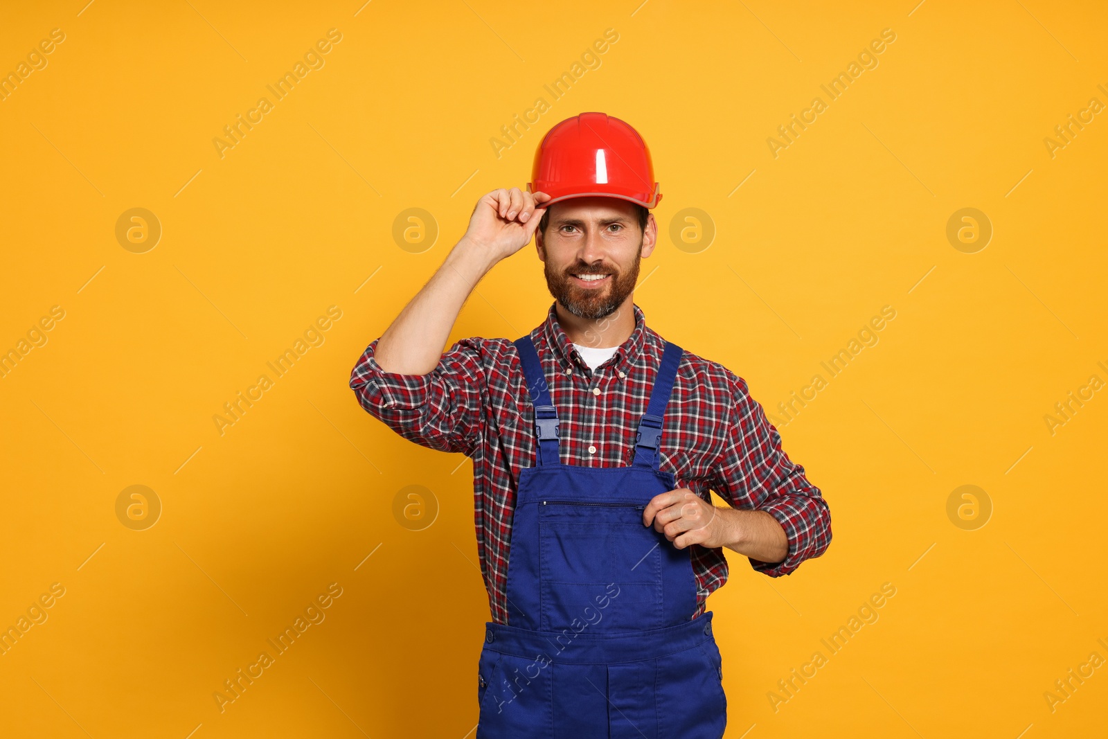 Photo of Professional builder in uniform on yellow background