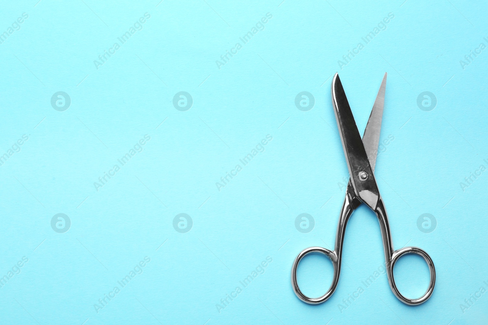 Photo of Pair of sharp scissors on color background, top view. Space for text