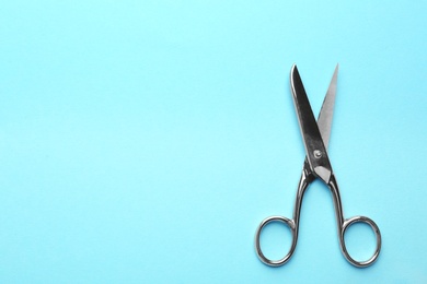 Photo of Pair of sharp scissors on color background, top view. Space for text