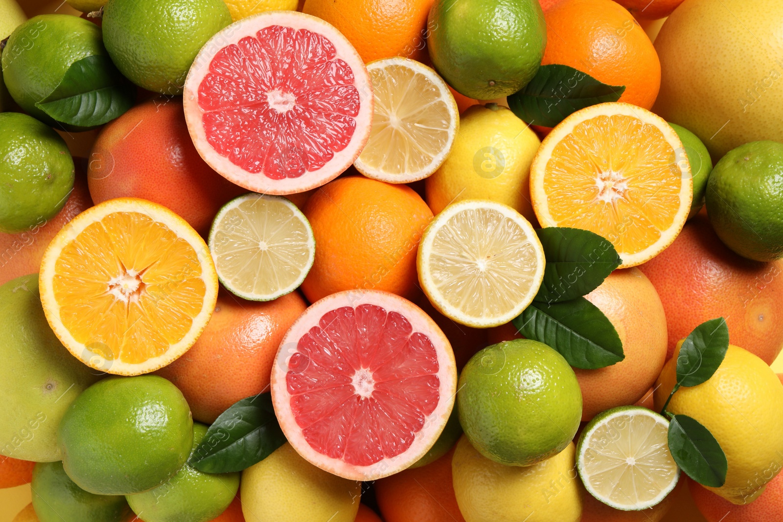 Photo of Different fresh citrus fruits and leaves as background, top view