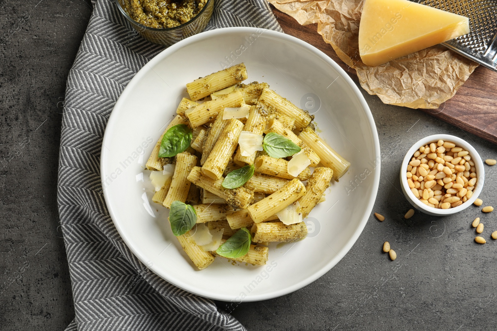 Photo of Flat lay composition with plate of delicious basil pesto pasta on gray table