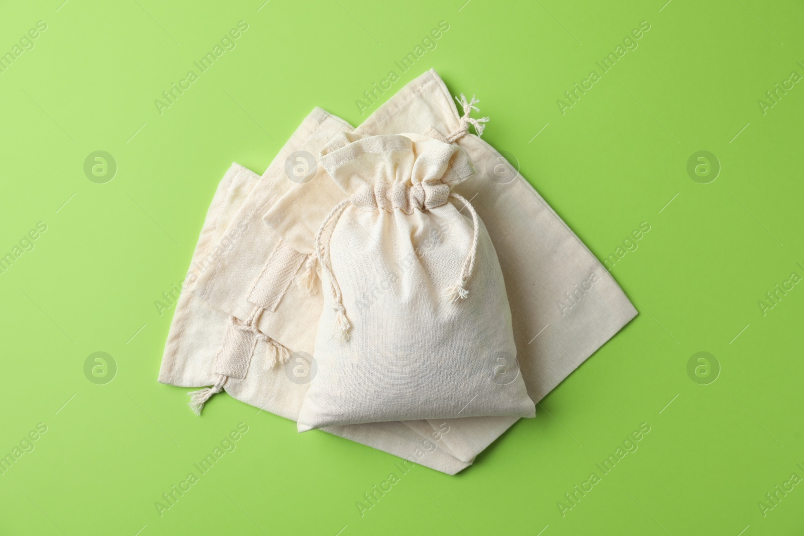 Photo of Cotton eco bags on light green background, flat lay