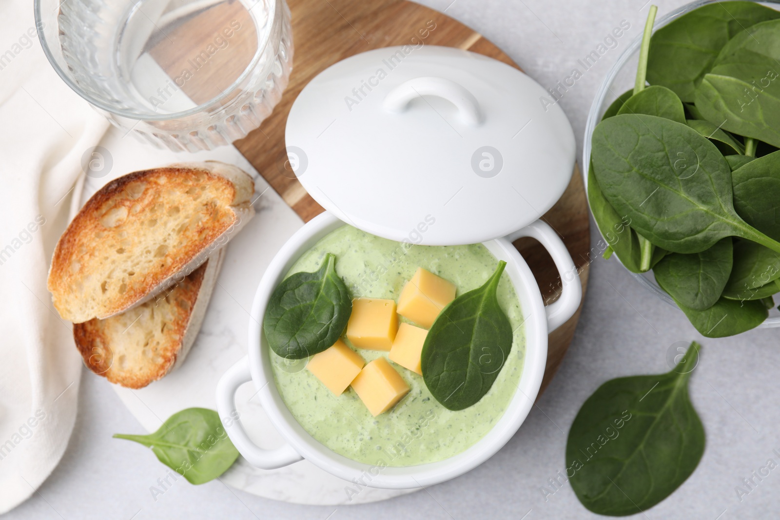 Photo of Delicious spinach cream soup with cheese in bowl on light grey table, flat lay