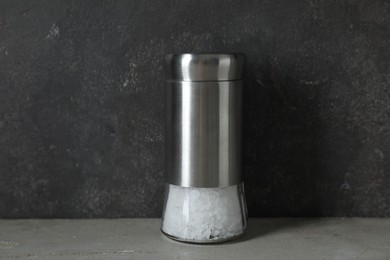 Photo of Salt shaker on light table against grey background, closeup