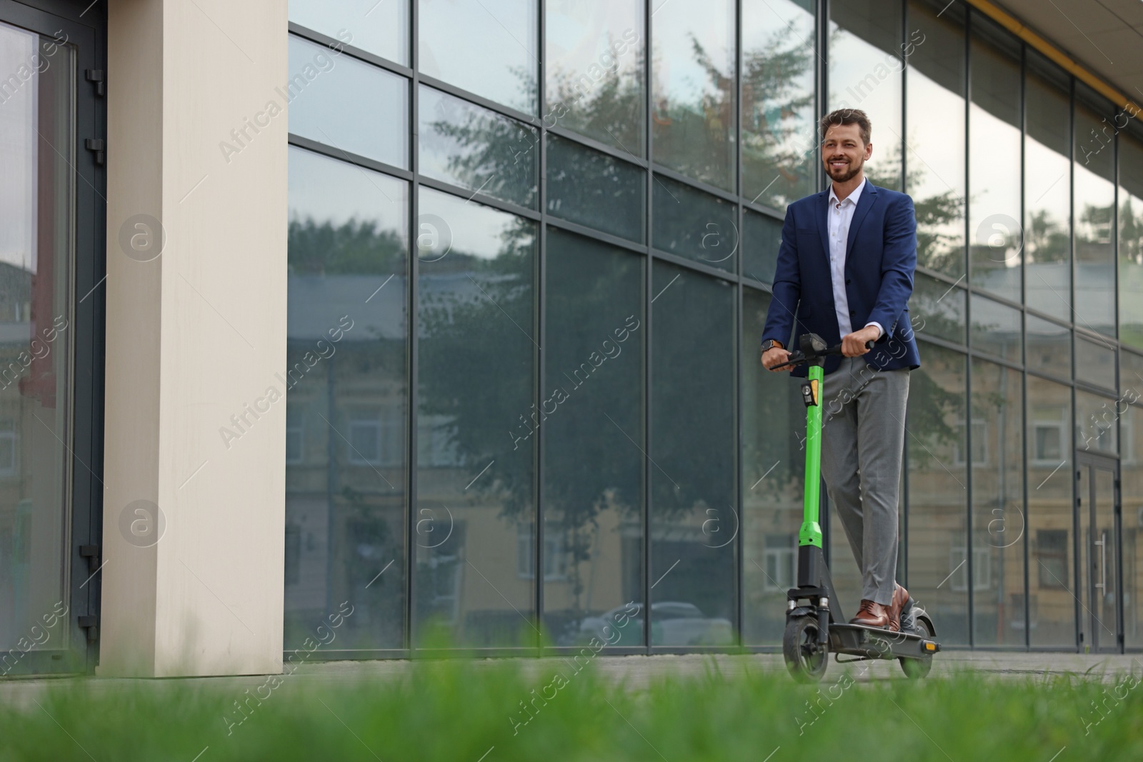 Photo of Businessman riding modern kick scooter on city street, space for text