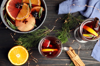 Tasty mulled wine with spices on wooden table, flat lay