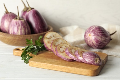 Photo of Cut ripe eggplant and parsley on white wooden table