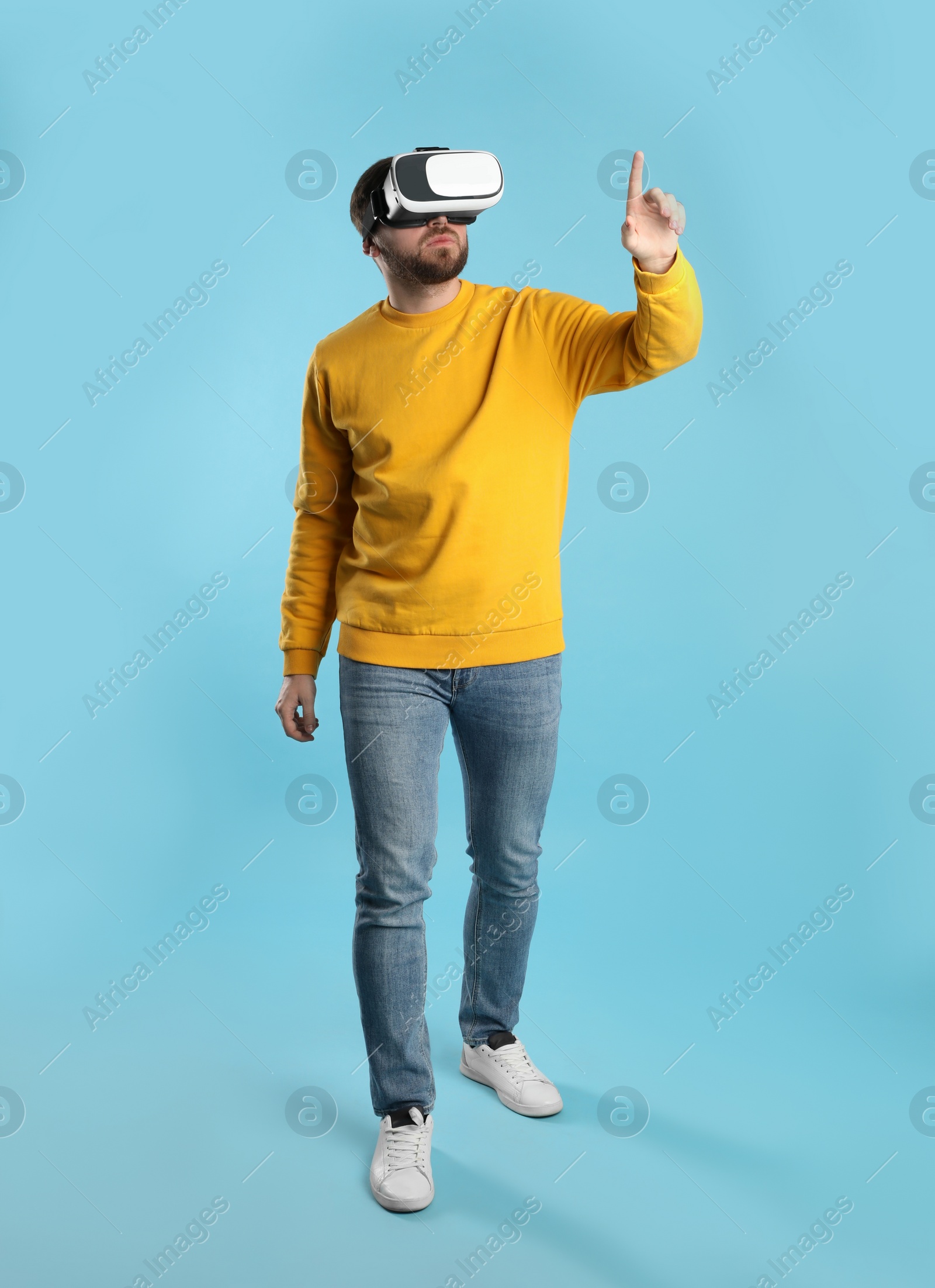 Photo of Man using virtual reality headset on light blue background