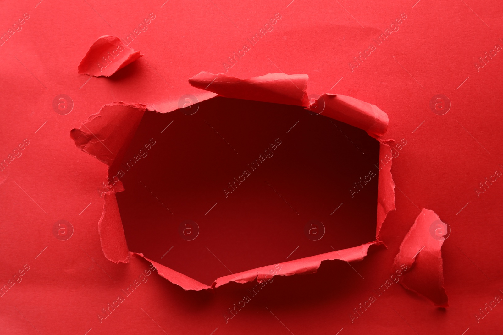 Photo of Hole in red paper on color background