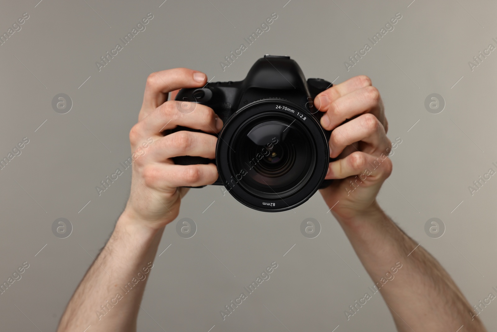 Photo of Photographer holding camera on grey background, closeup