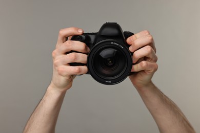 Photographer holding camera on grey background, closeup