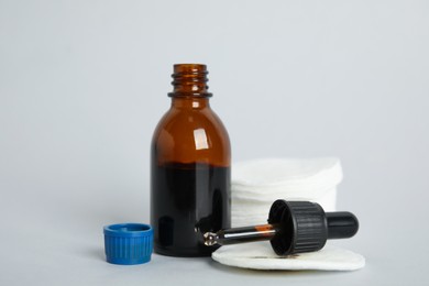 Photo of Bottle of medical iodine, dropper and cotton pads on grey background