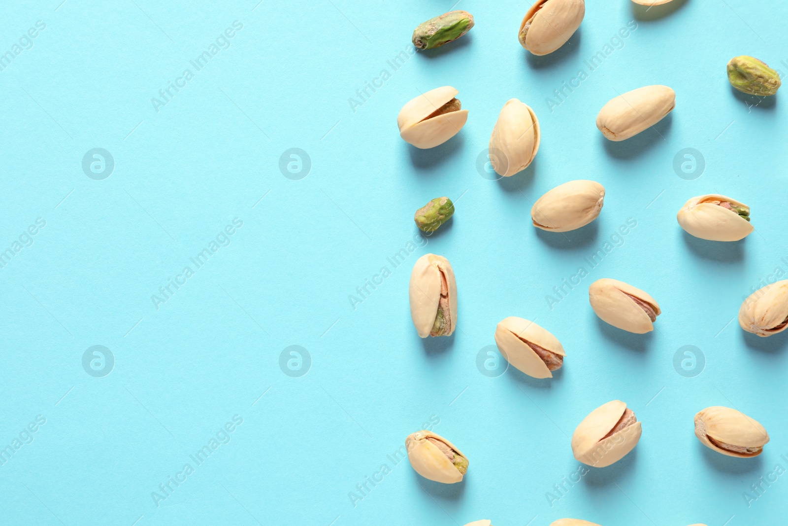 Photo of Composition with organic pistachio nuts on color background, flat lay. Space for text