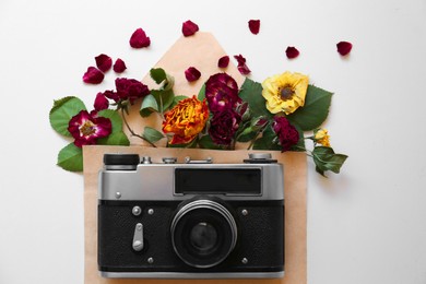 Photo of Flat lay composition with beautiful dried flowers in envelope and vintage camera on white background