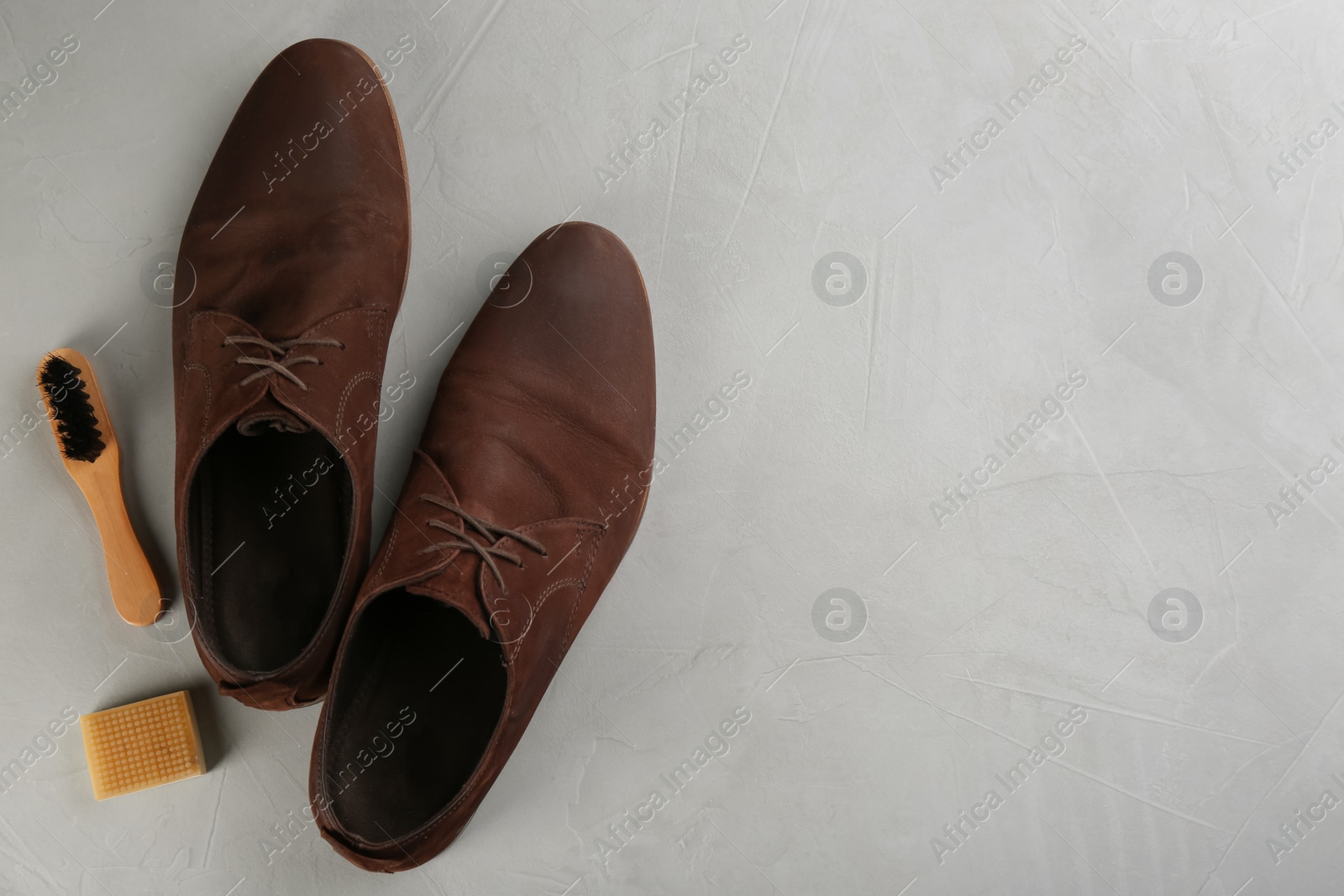 Photo of Stylish footwear with shoe care accessories on light grey stone table, flat lay. Space for text