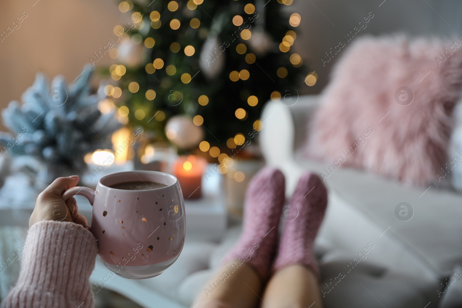 Photo of Woman with cup of cocoa in room decorated for Christmas, closeup