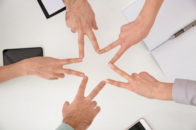 Photo of Young people showing victory gesture over table, top view