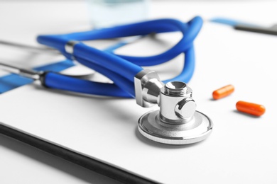 Stethoscope, clipboard and pills, closeup. Medical equipment