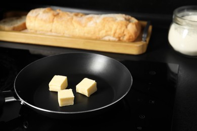 Photo of Melting butter in frying pan, bread and flour on black table