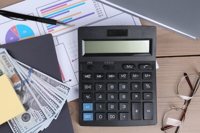 Photo of Dollar banknotes, calculator, papers, glasses, pen and notebook on wooden table, flat lay. Pension planning