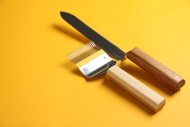 Photo of Uncapping fork and knife on yellow background, space for text. Beekeeping tools
