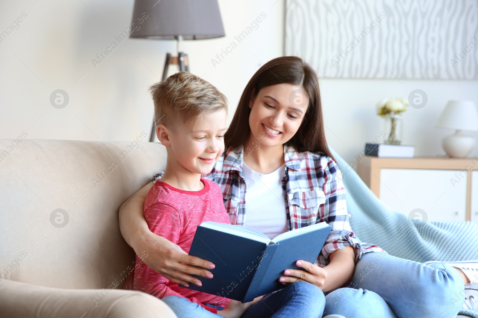 Photo of Little boy and his mother reading book, indoors