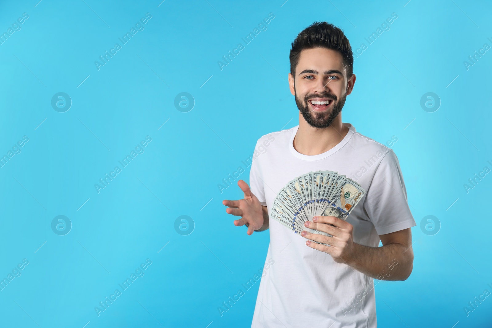 Photo of Portrait of happy young man with money on color background. Space for text