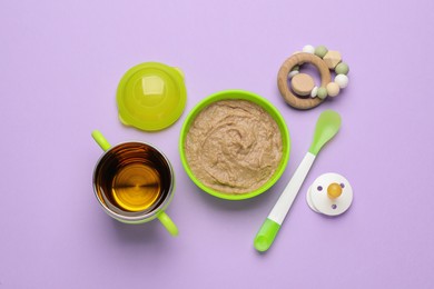 Healthy baby food in bowl and accessories on violet background, flat lay