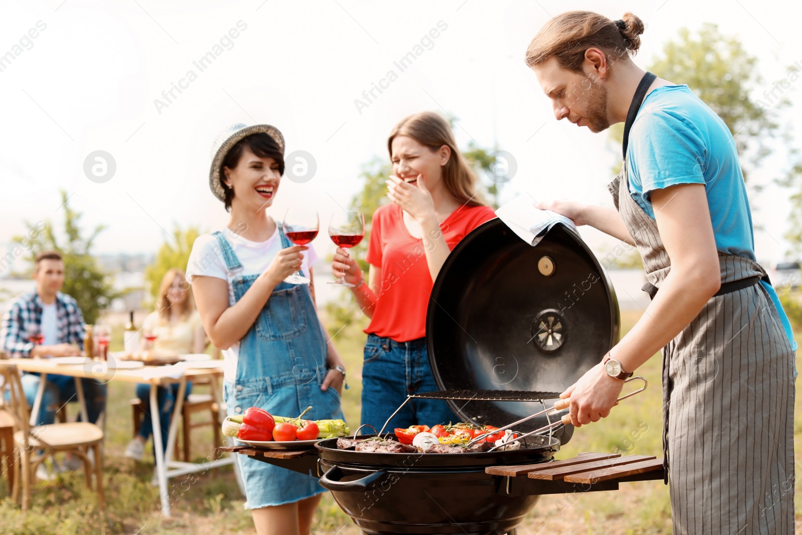 Photo of Young people having barbecue with modern grill outdoors