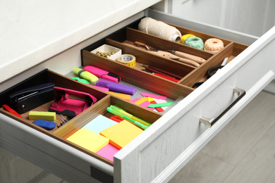 Stationery and sewing accessories in open desk drawer indoors