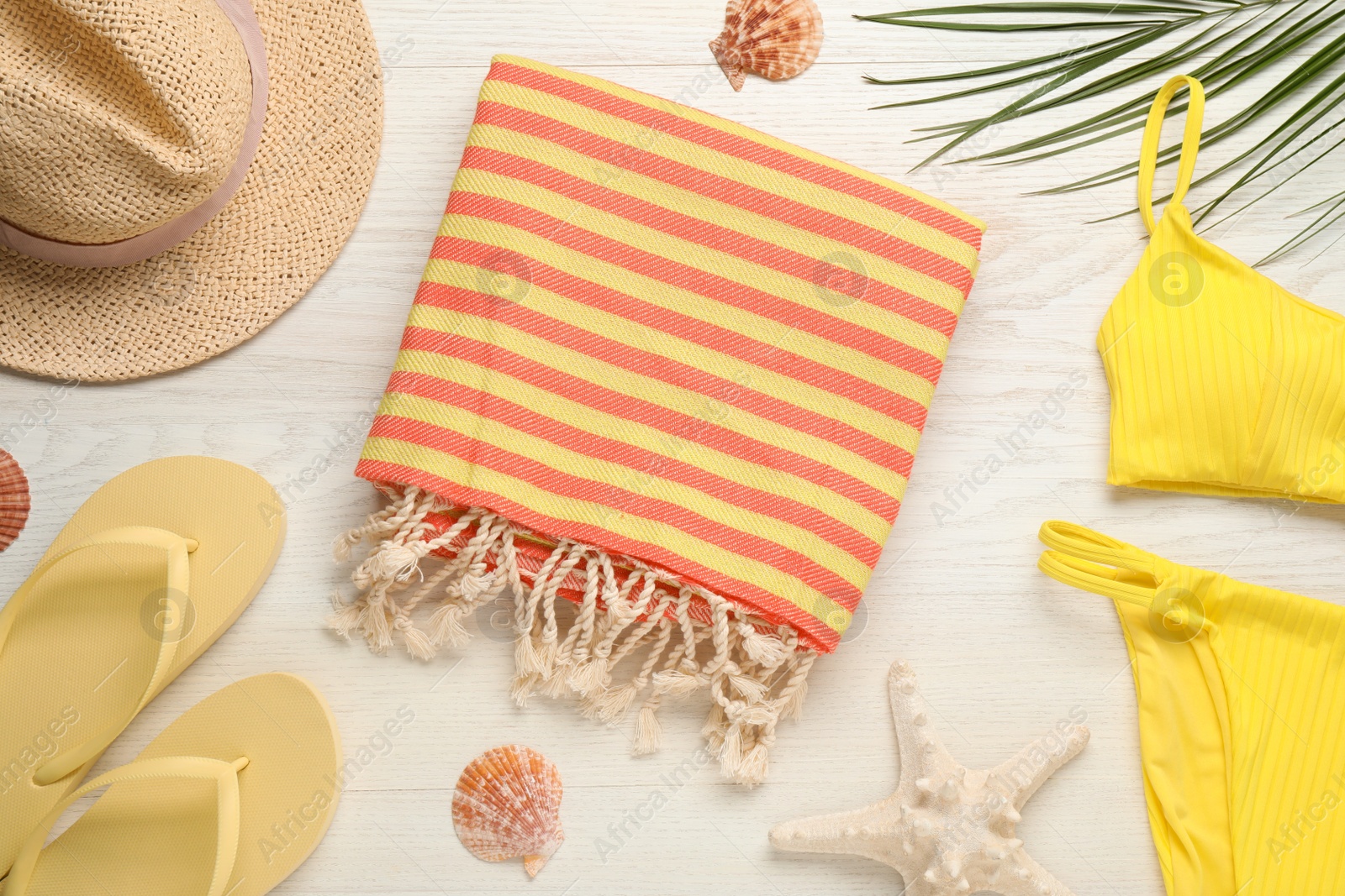 Photo of Towel and different beach accessories on white wooden background, flat lay