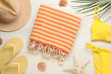 Towel and different beach accessories on white wooden background, flat lay