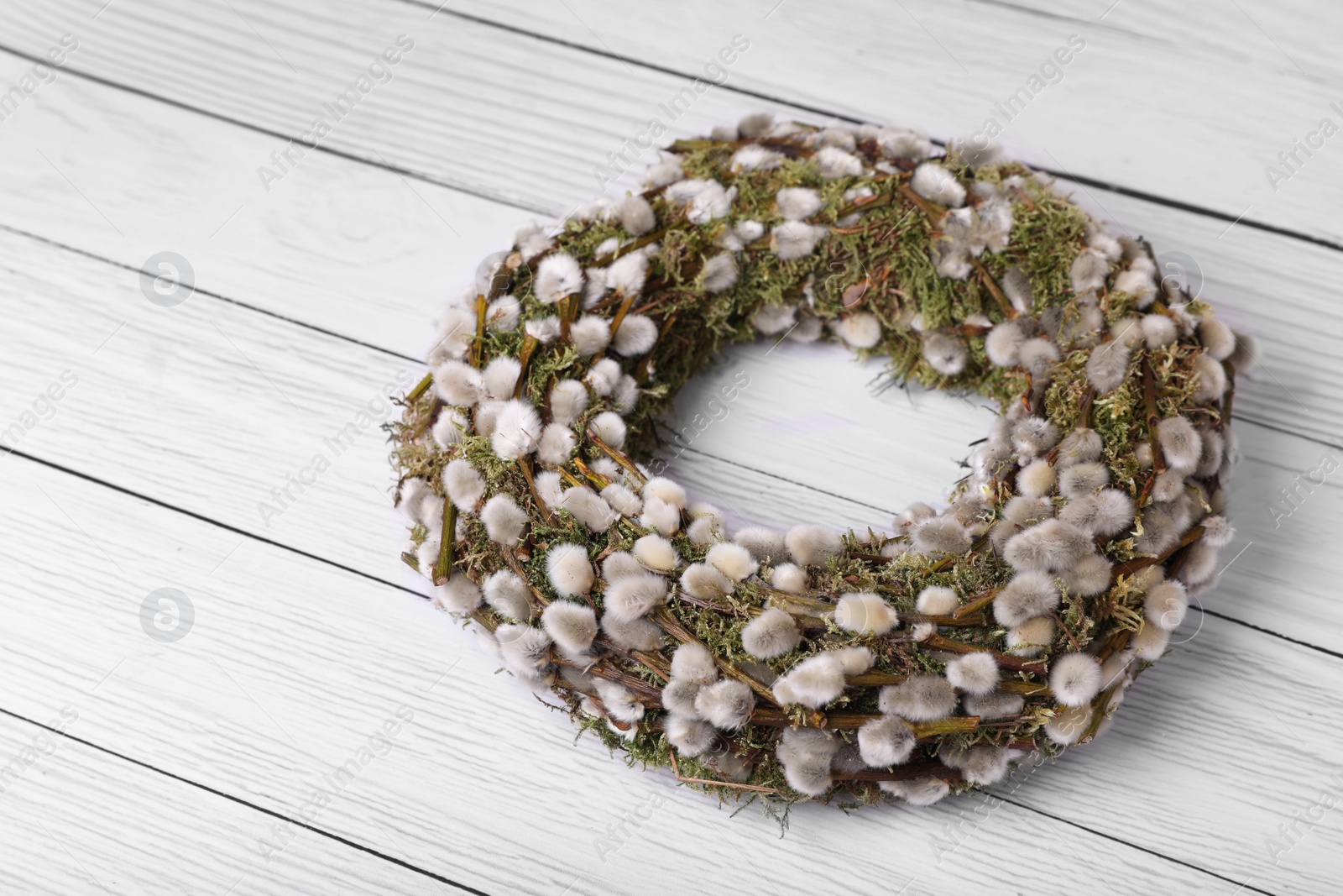 Photo of Wreath made of beautiful willow flowers on white wooden table. Space for text
