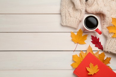 Photo of Cup of hot coffee, book, sweater and autumn leaves on white wooden table, flat lay. Space for text