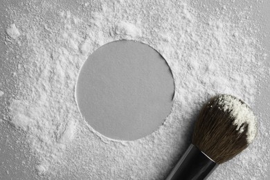 Frame made of rice loose face powder and makeup brush on light grey background, top view. Space for text