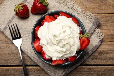 Photo of Bowl with delicious strawberries and whipped cream served on wooden table, flat lay