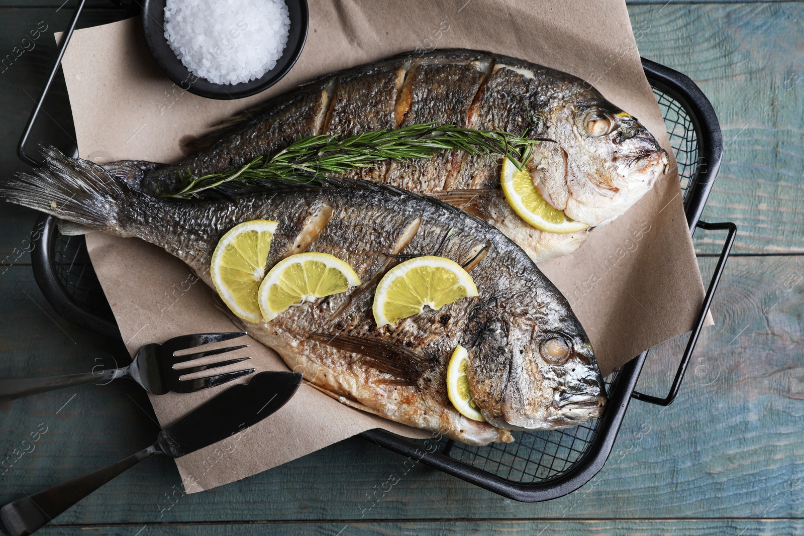 Photo of Delicious baked fish served on wooden rustic table, top view. Seafood