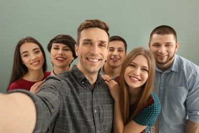 Photo of Happy friends taking selfie on color background