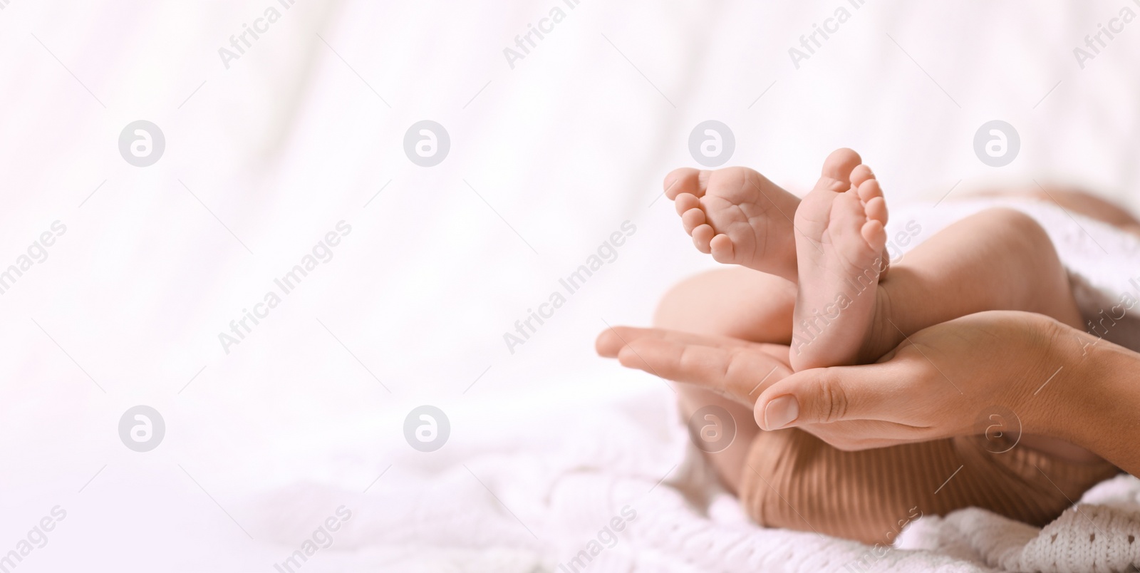 Image of Mother and her baby baby on white knitted blanket, closeup. Banner design with space for text