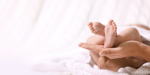 Image of Mother and her baby baby on white knitted blanket, closeup. Banner design with space for text