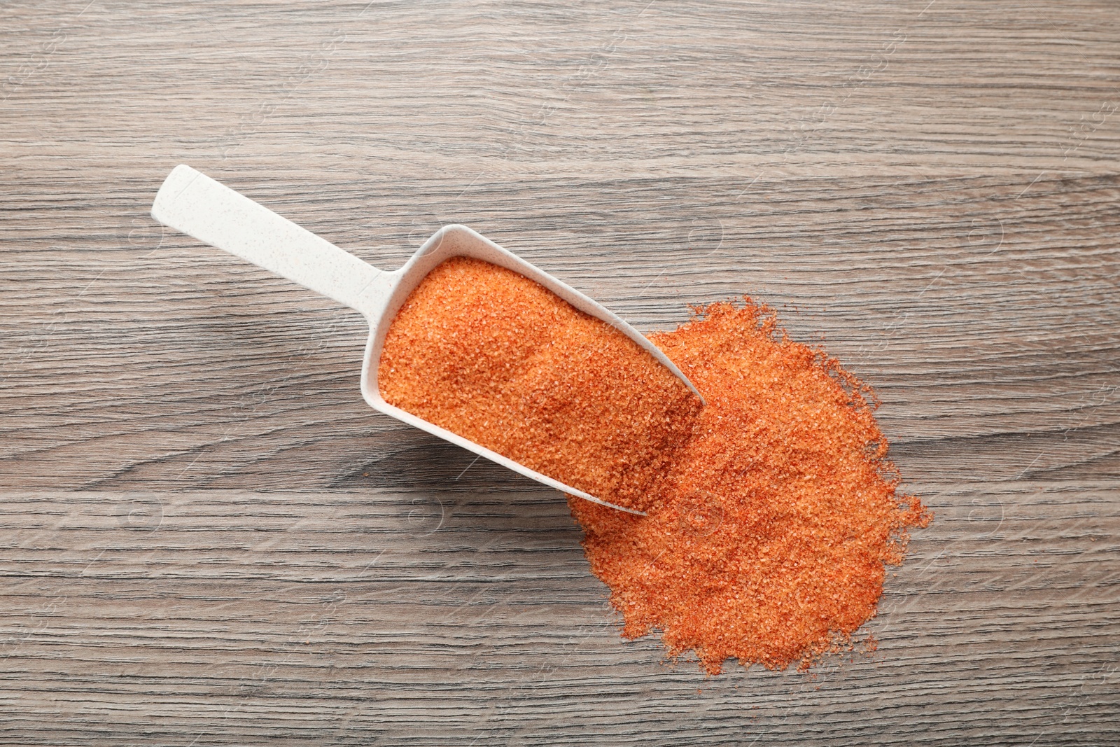 Photo of Pink salt with spices and scoop on wooden table, top view