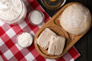 Photo of Compressed yeast, salt, egg, flour and dough on wooden table, flat lay