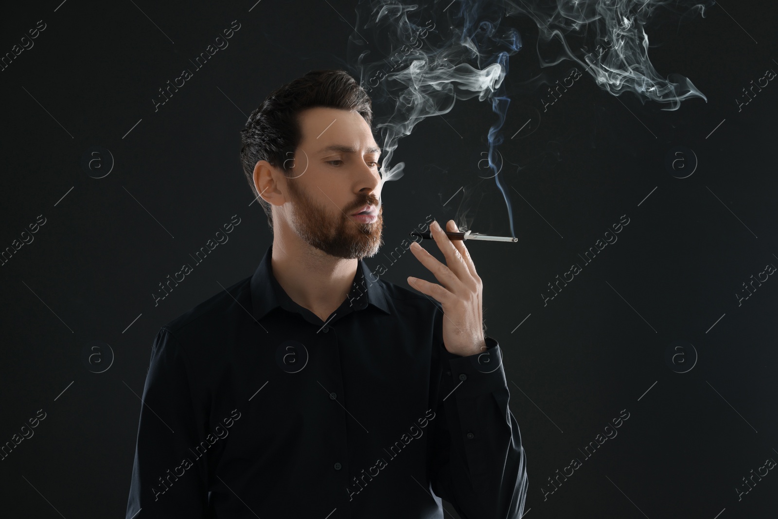 Photo of Man using cigarette holder for smoking on black background, space for text