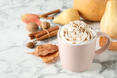 Photo of Cup with tasty pumpkin spice latte on white marble table. Space for text