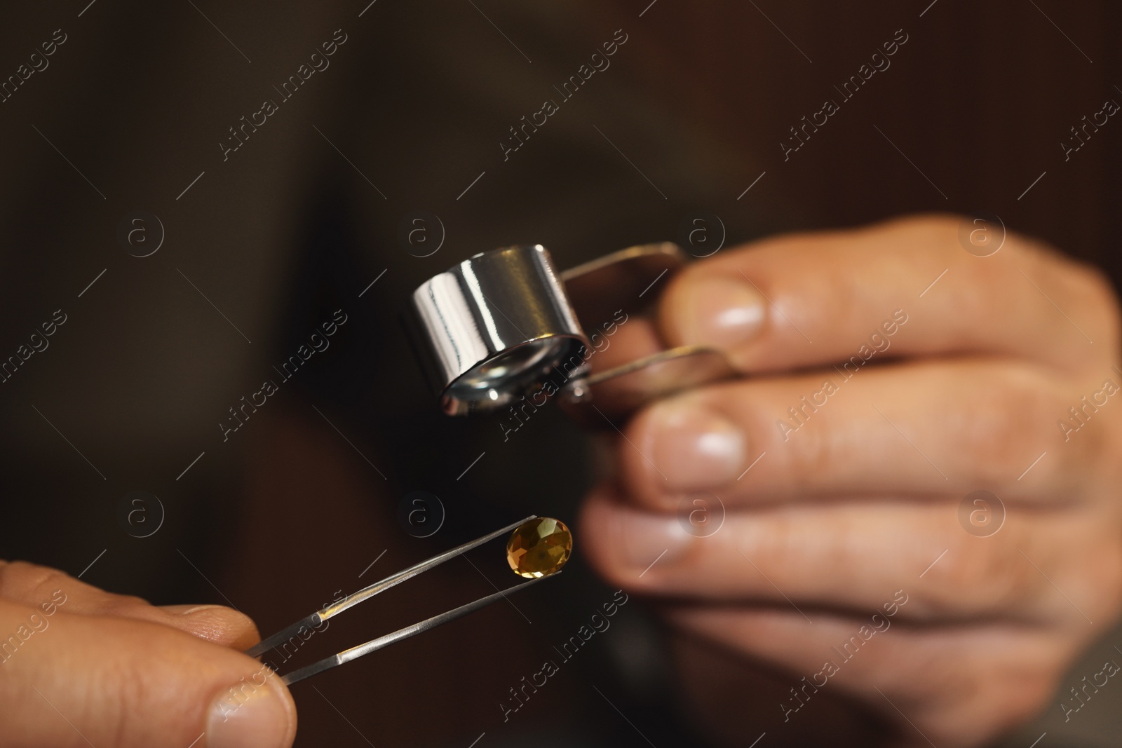 Photo of Jeweler working with gemstone on blurred background, closeup