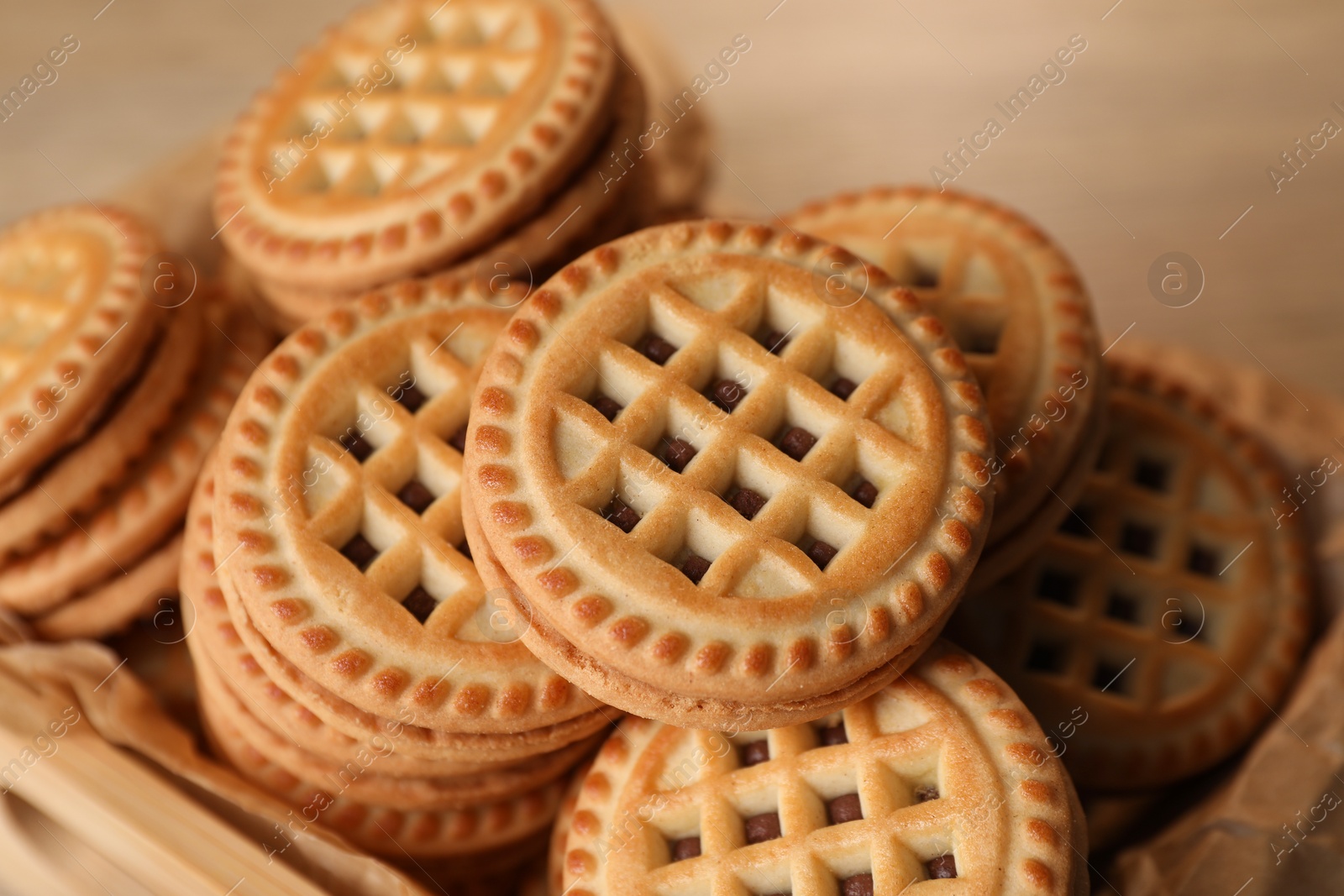 Photo of Tasty sandwich cookies with cream in wooden tray, closeup