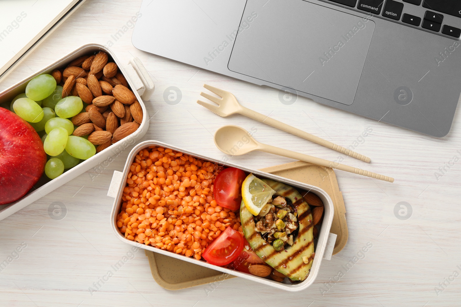 Photo of Healthy products high in vegetable fats near laptop on light wooden table, flat lay