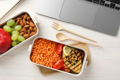 Healthy products high in vegetable fats near laptop on light wooden table, flat lay